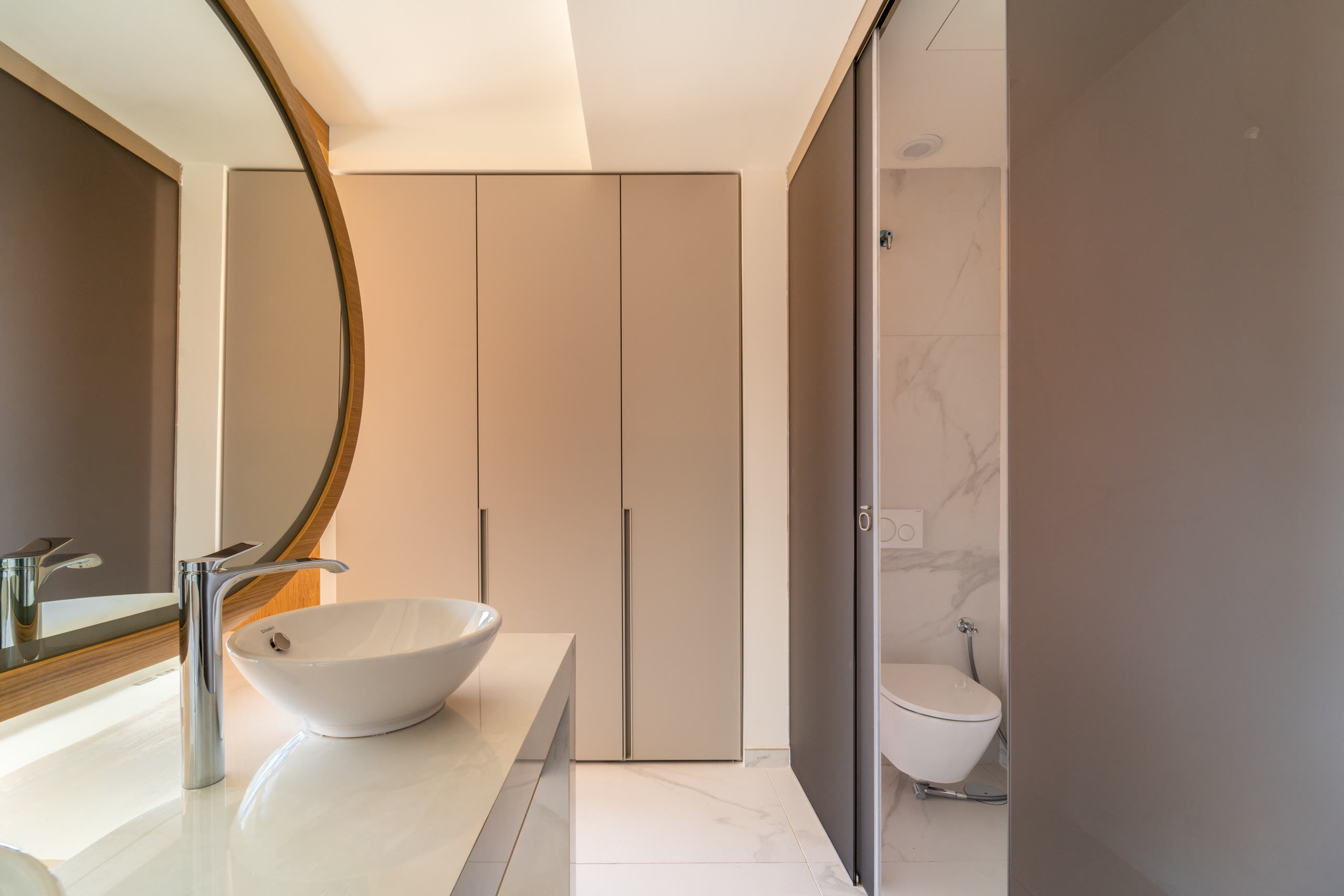 Bathroom vanity with a round mirror and soft neutral tones