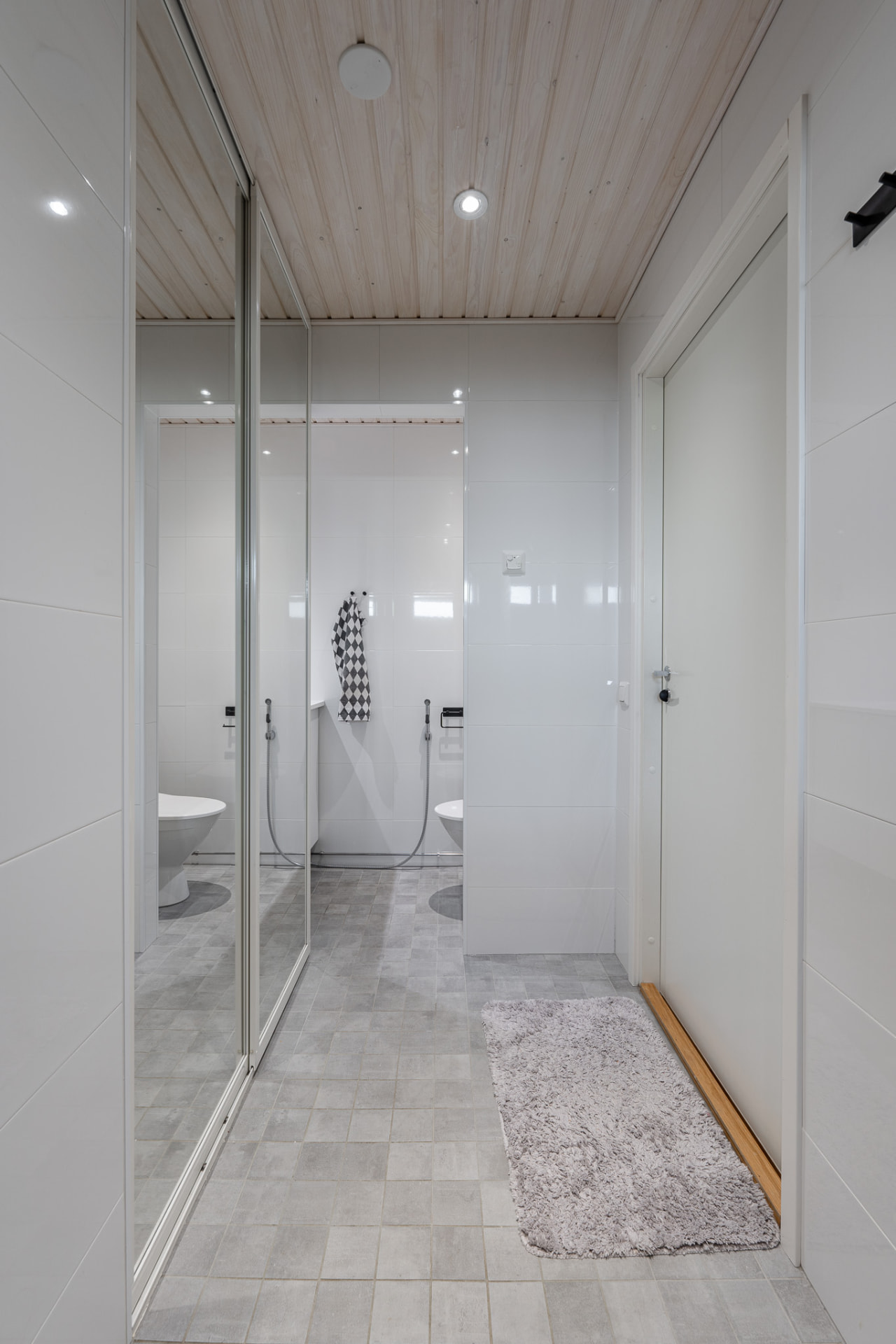 Renovated bathroom with a mirrored wardrobe, white wall tiles and soft grey floor tiles