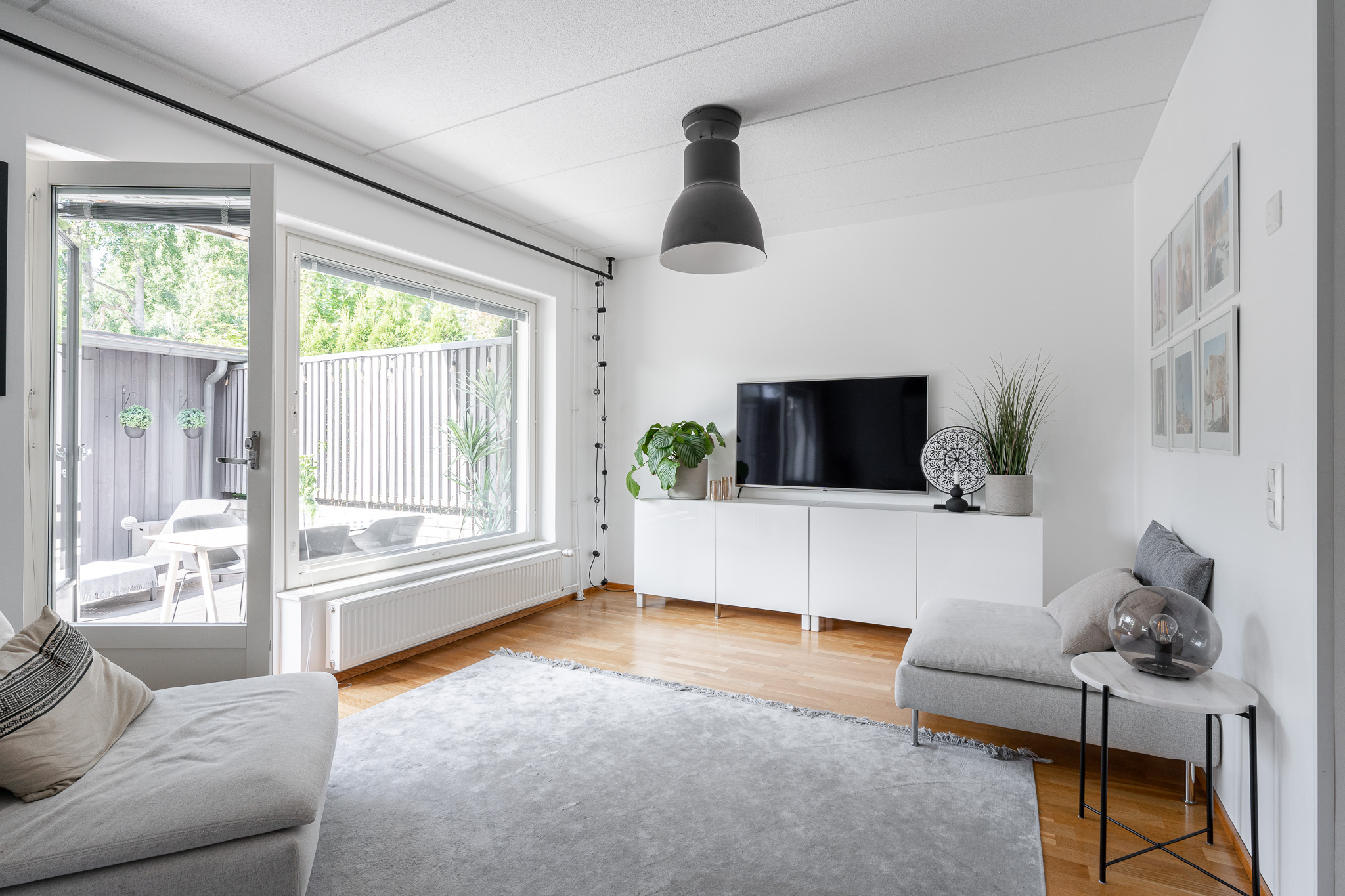 Calm living room in soft whites with a picture window onto the fenced garden