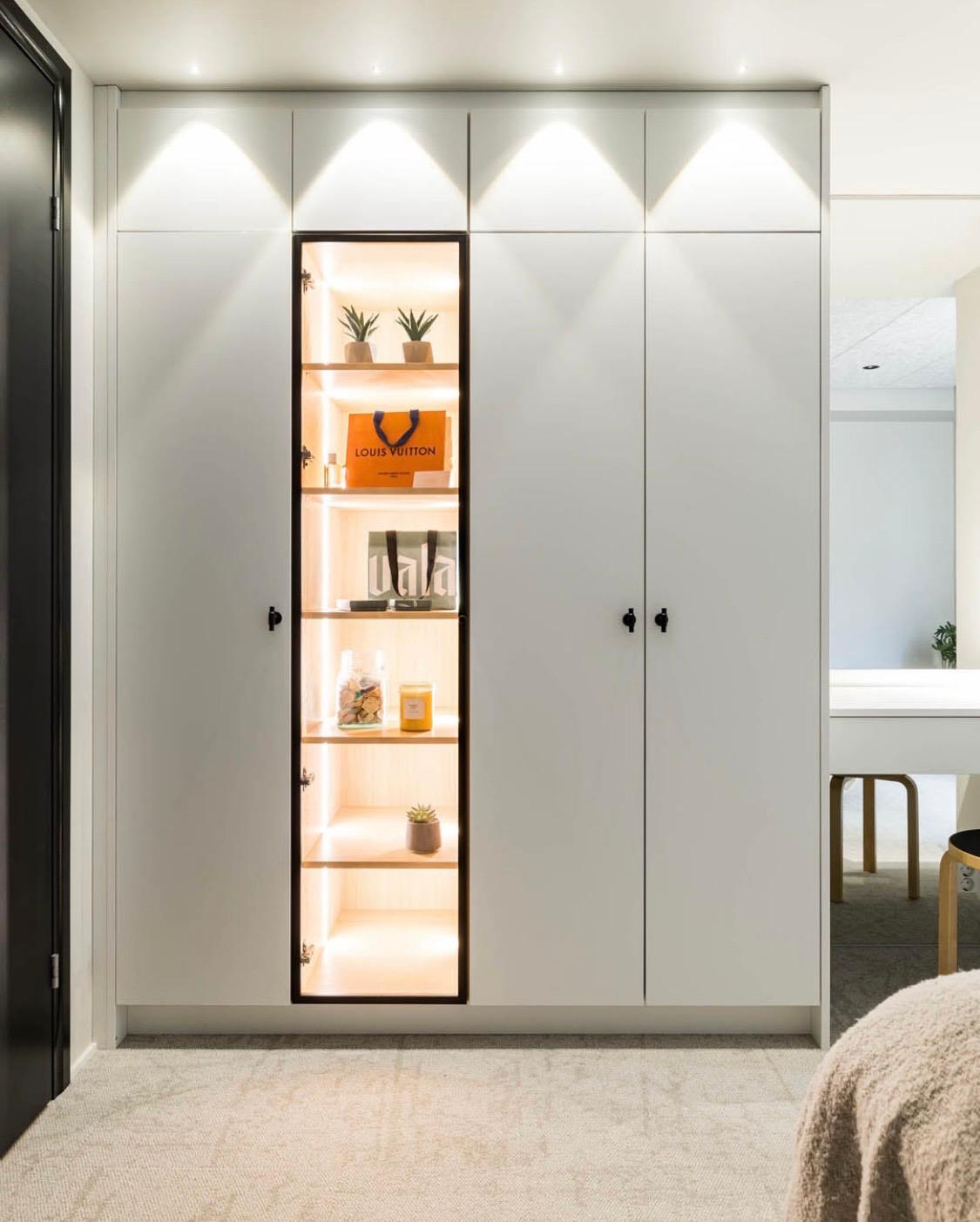 Illuminated wardrobe niche styled with ceramics, books and a Louis Vuitton box