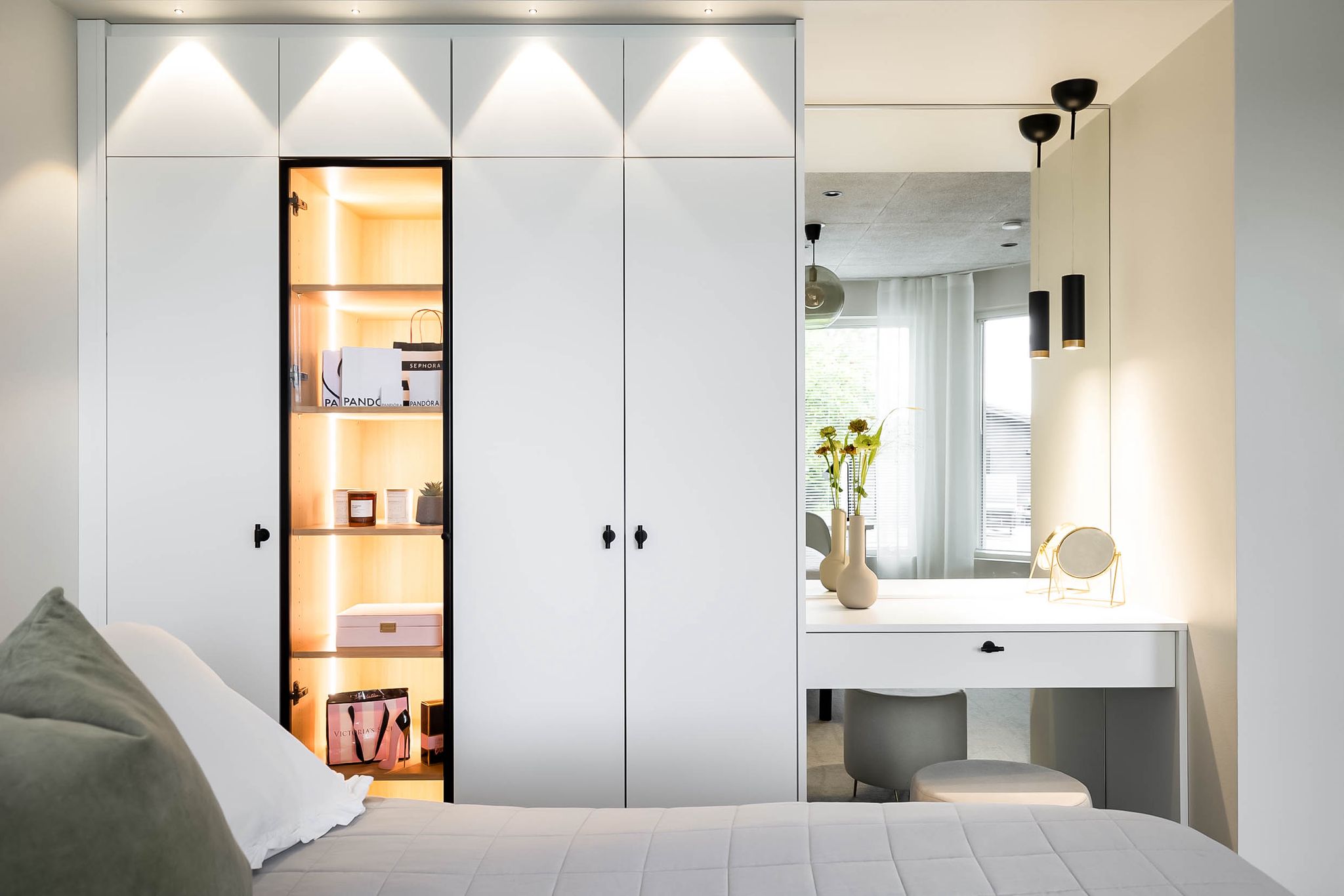 Wardrobe wall with an illuminated display niche beside a vanity table