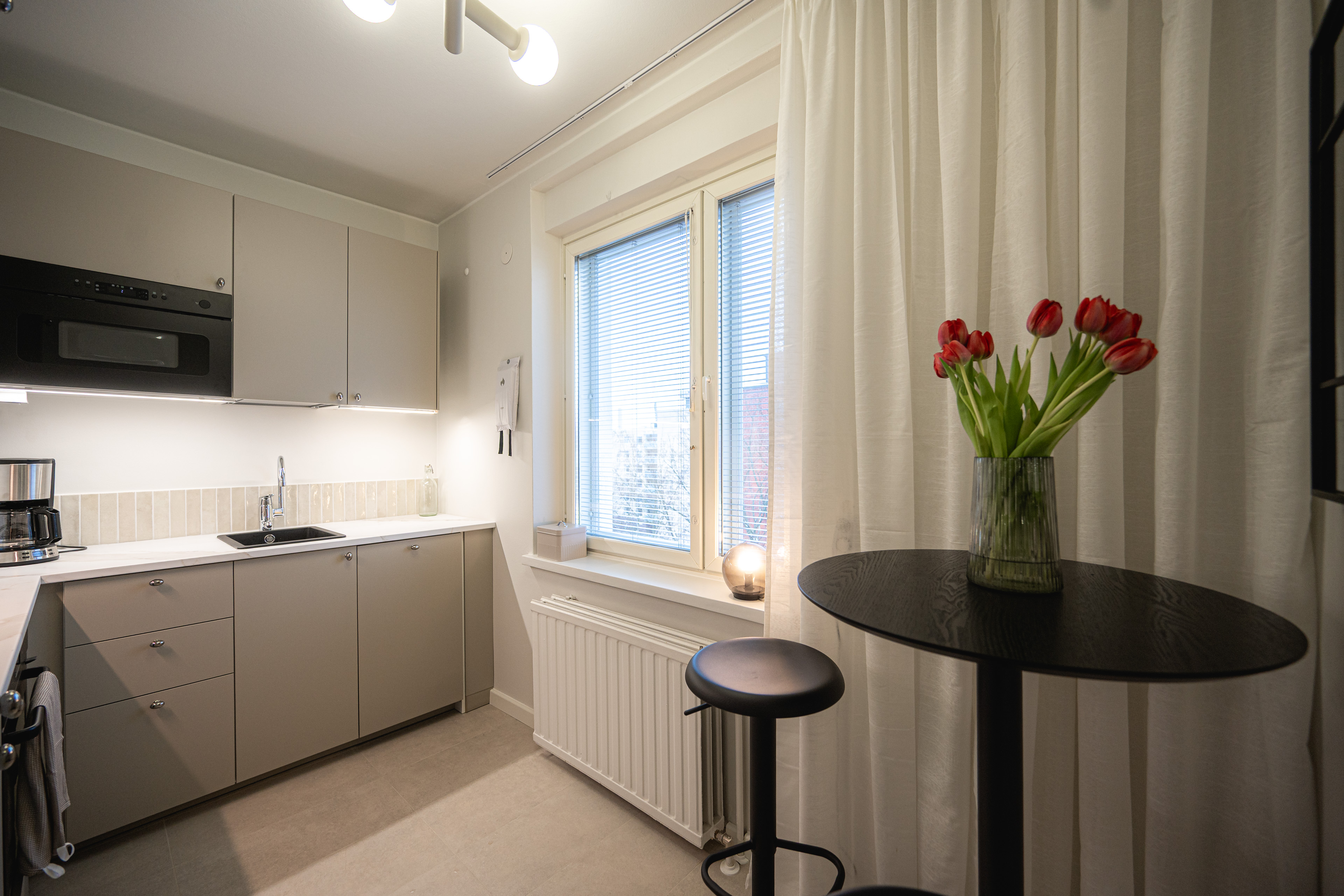 Compact kitchen in warm greige with a small breakfast table by the window