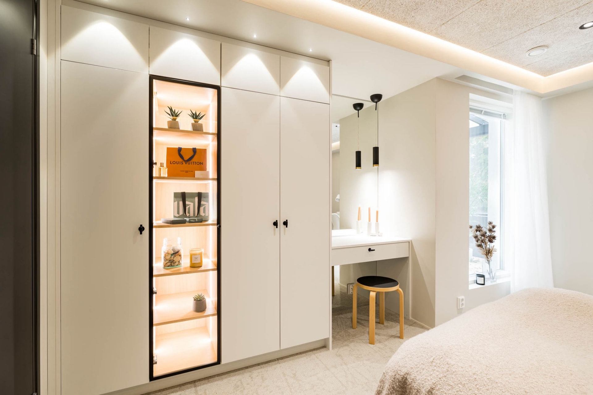 Bedroom wardrobe wall with an illuminated glass display niche and a compact dressing table