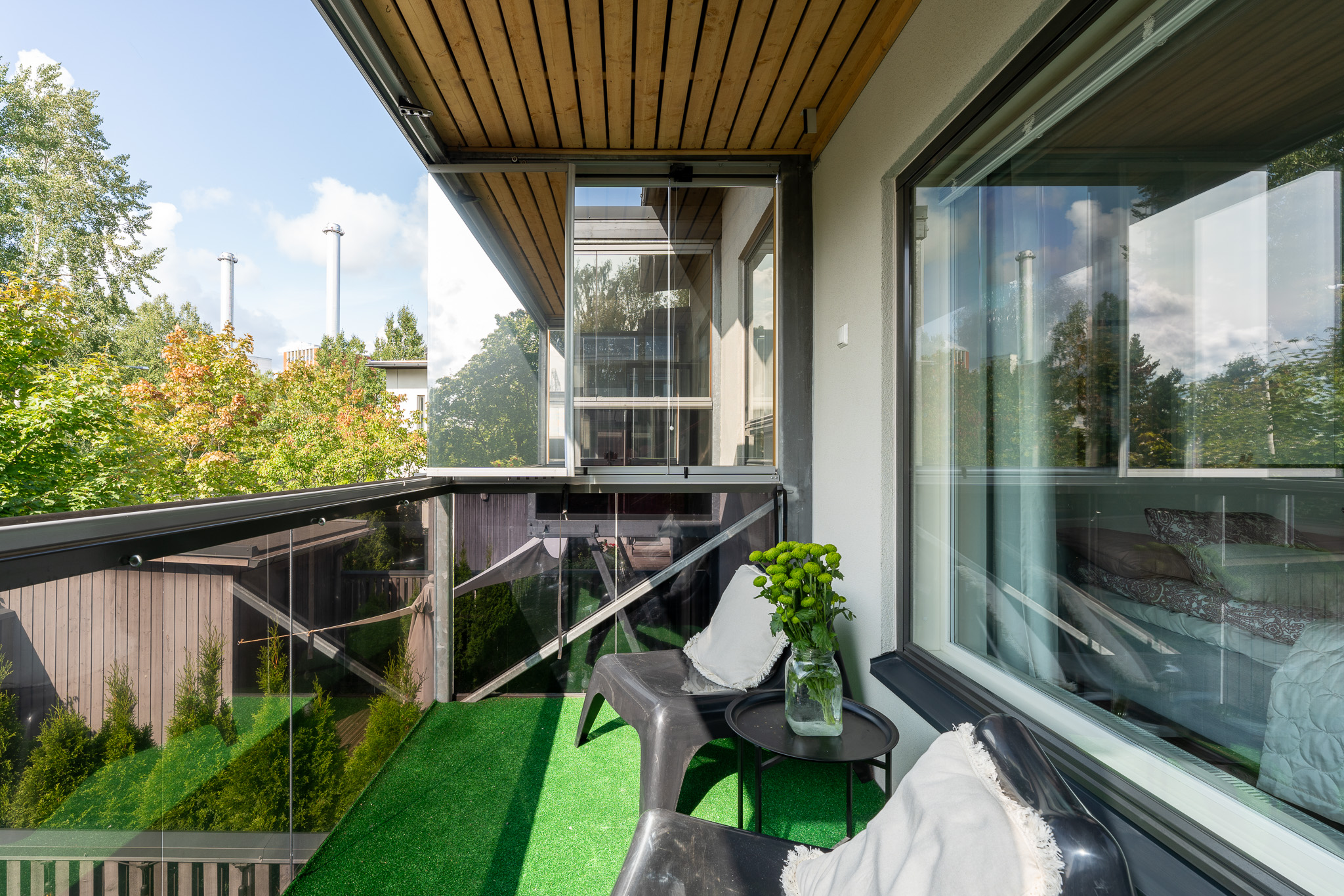 Upper balcony with a small seating nook and glass balustrade among the treetops