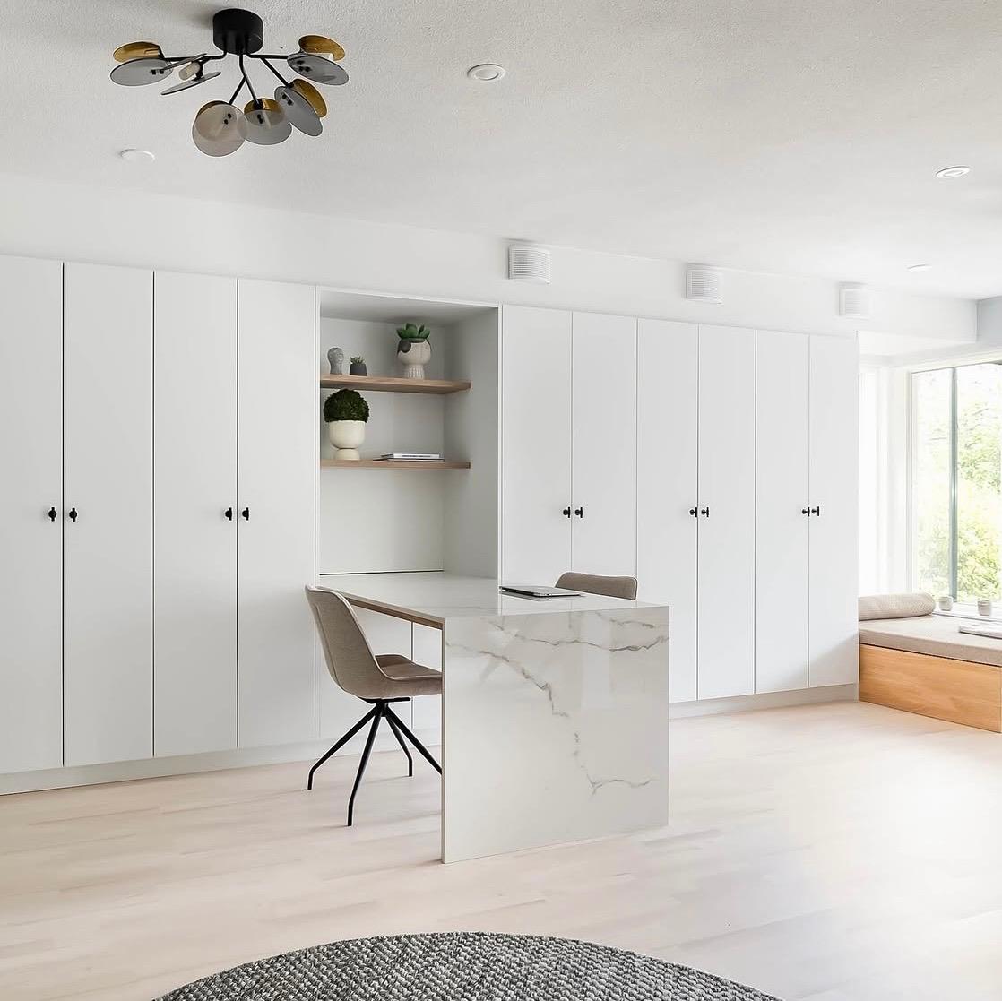 Full-height white wardrobe wall with an open shelf niche and a marble-topped desk