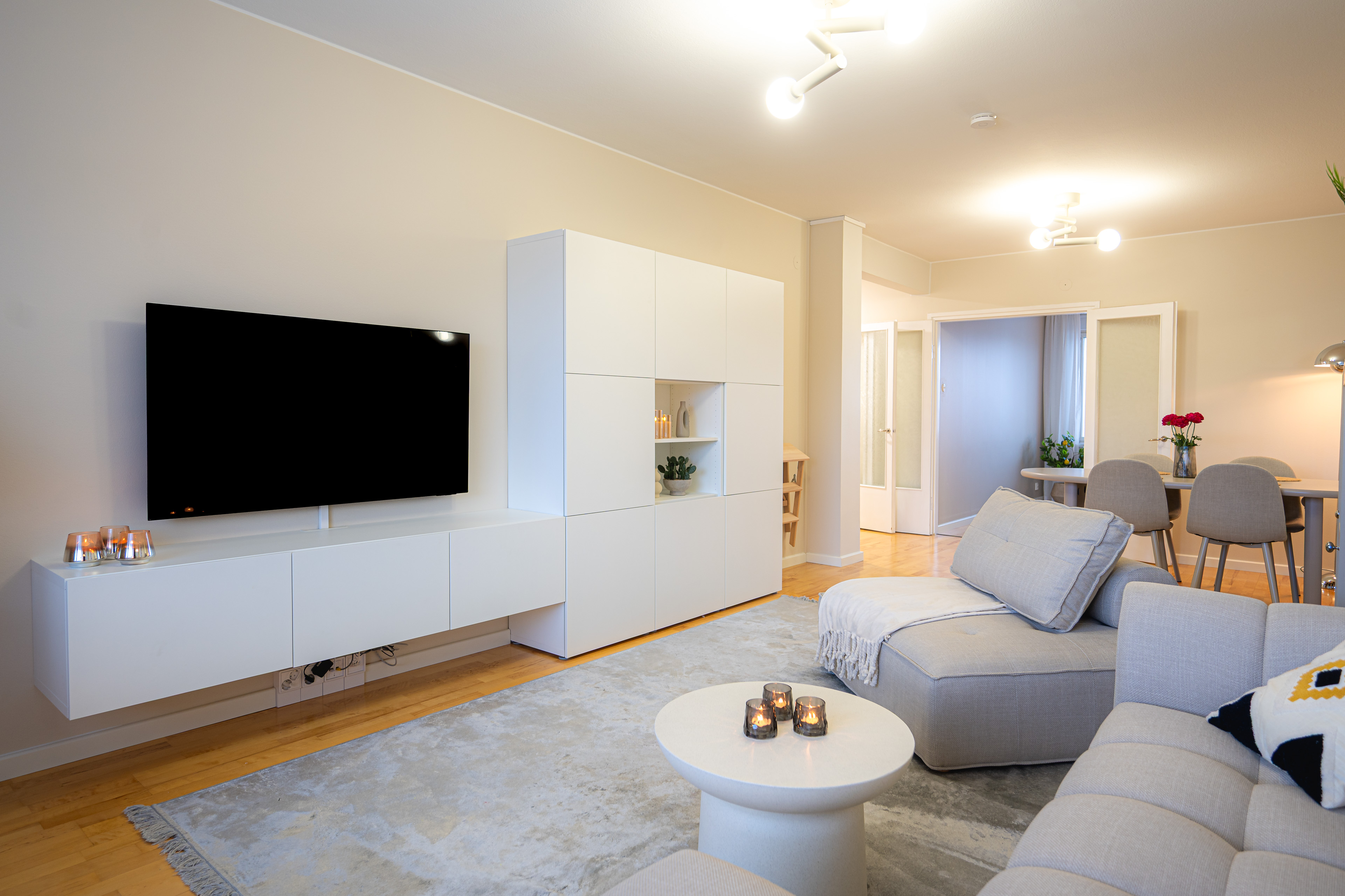 Light-filled living room with a pale grey sofa, white storage wall and oak floor