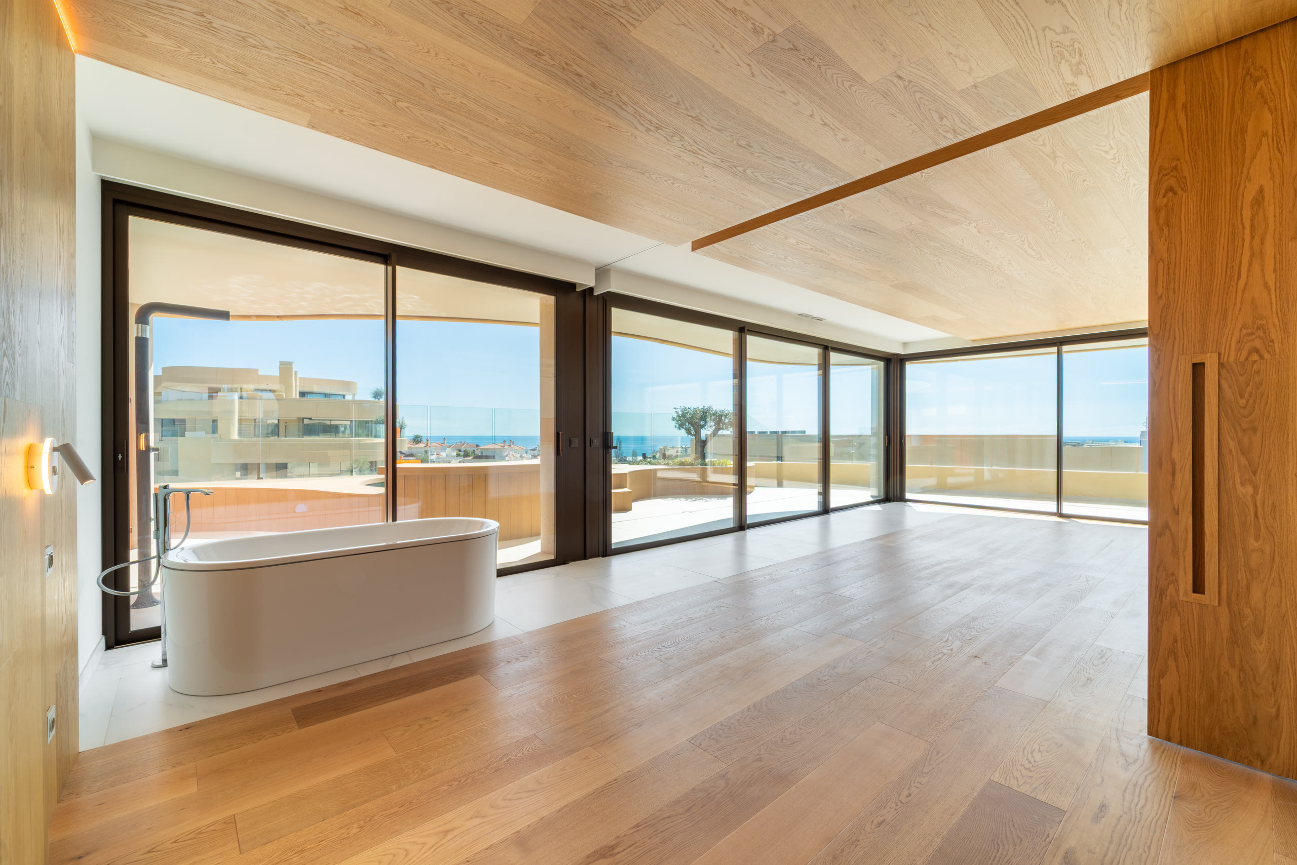 Bathtub set against floor-to-ceiling windows with a sea view