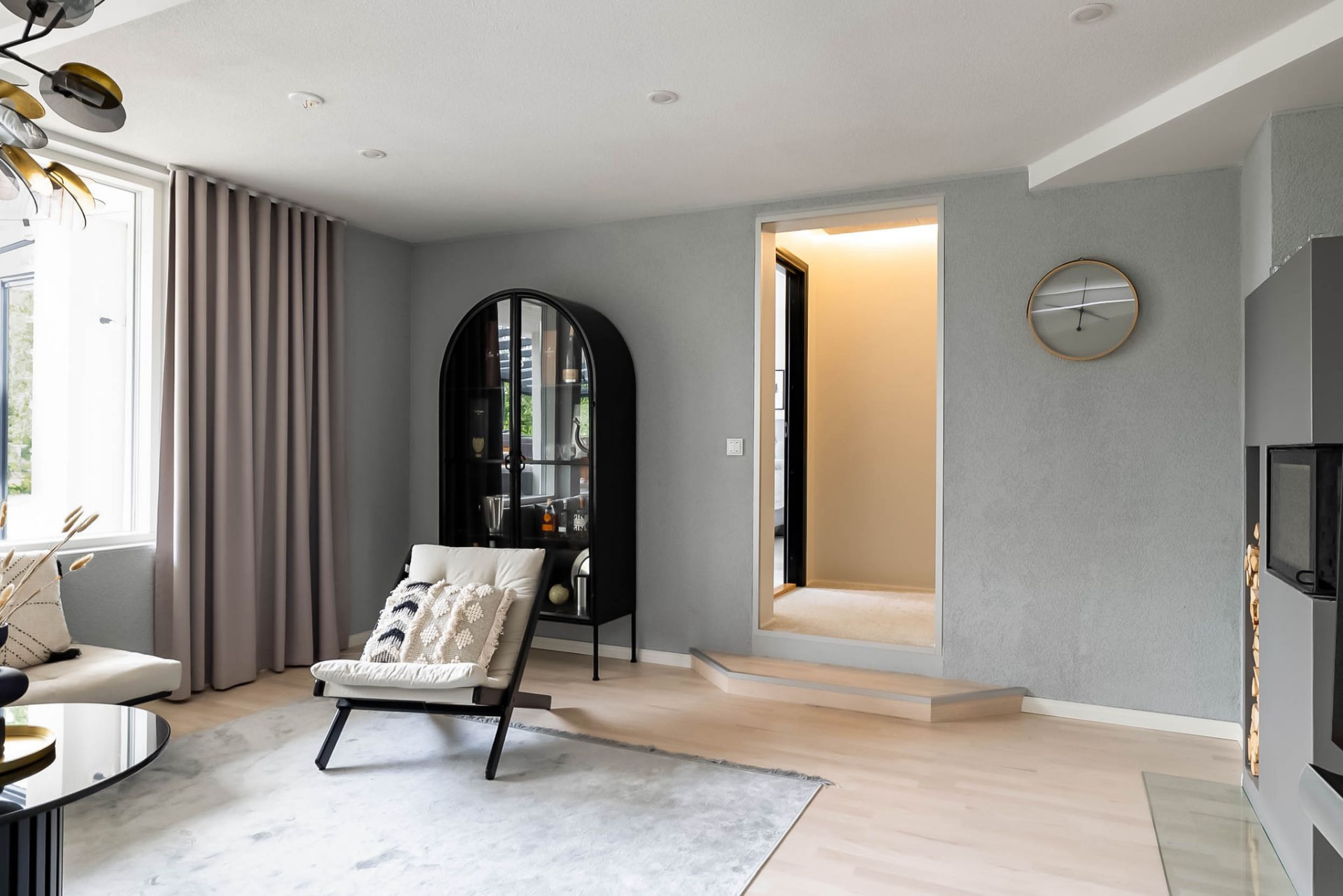 Living room with soft grey walls, linen curtain and a black arched cabinet