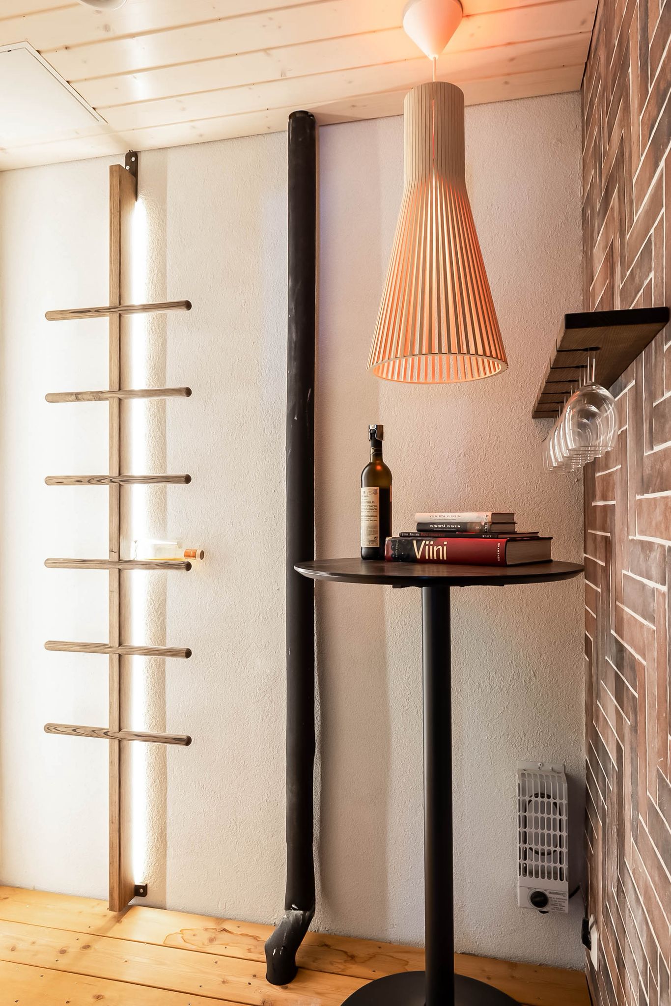 Entry detail with a woven pendant, brick wall and a small side table