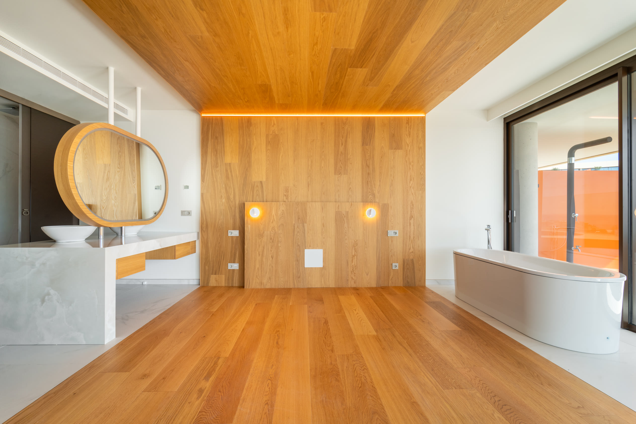 Master suite with warm wood panelling and a freestanding bathtub