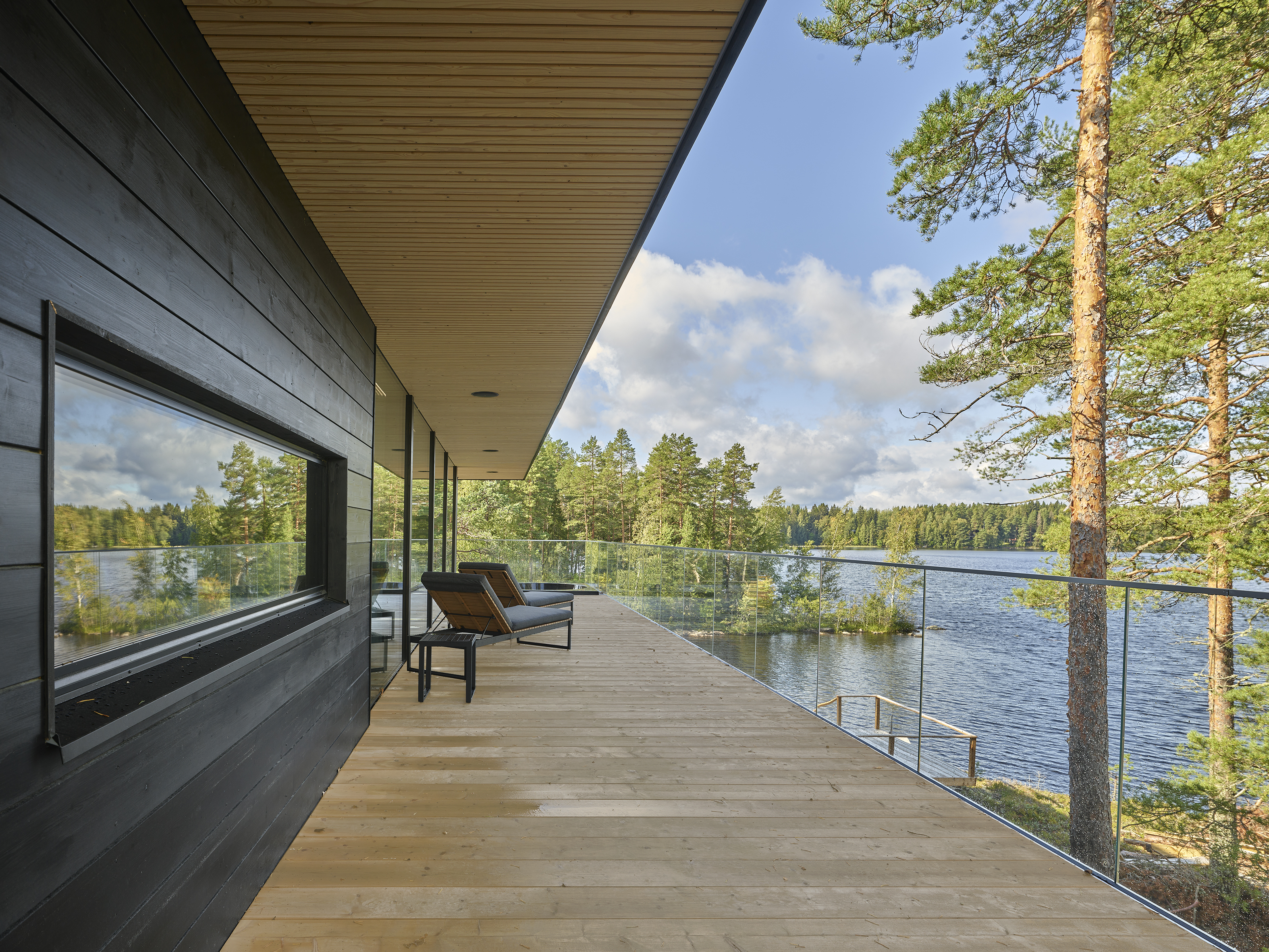 Long timber terrace with a glass balustrade overlooking the lake