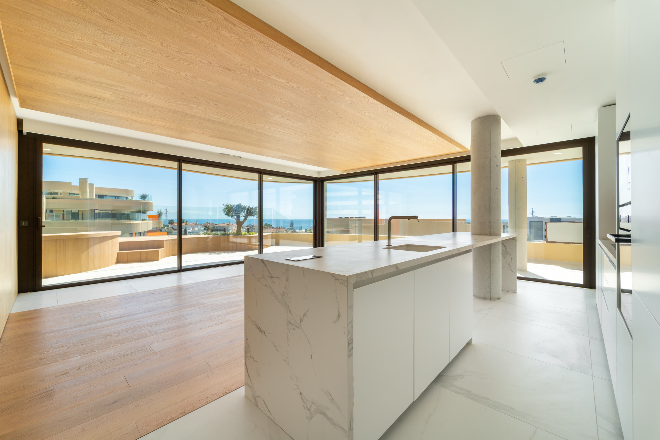Kitchen with a marble island and glass walls framing the Mediterranean view