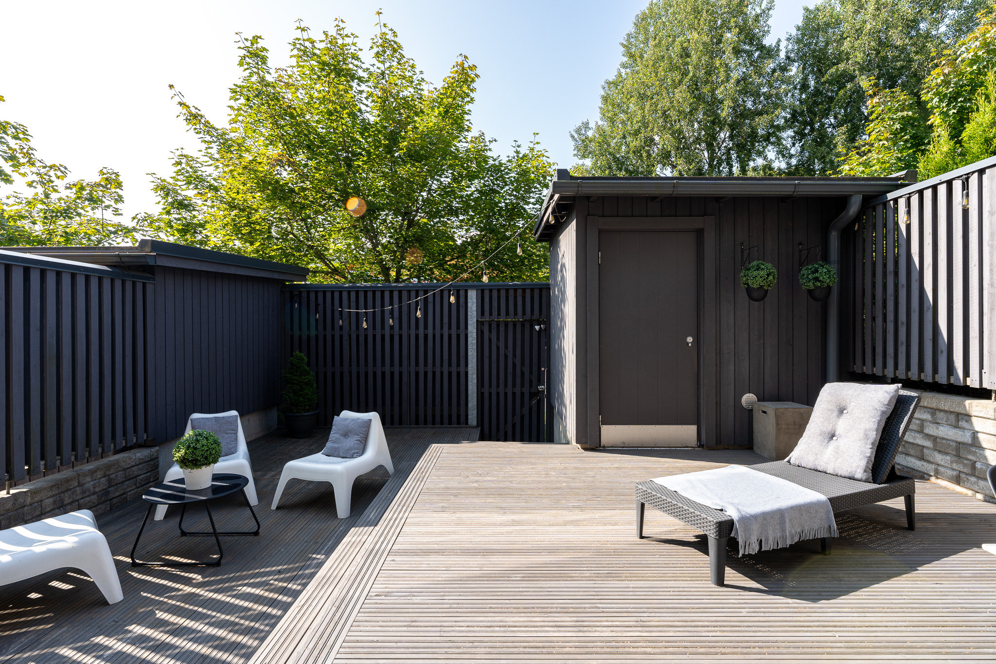 Timber deck with a black garden shed and low sun loungers